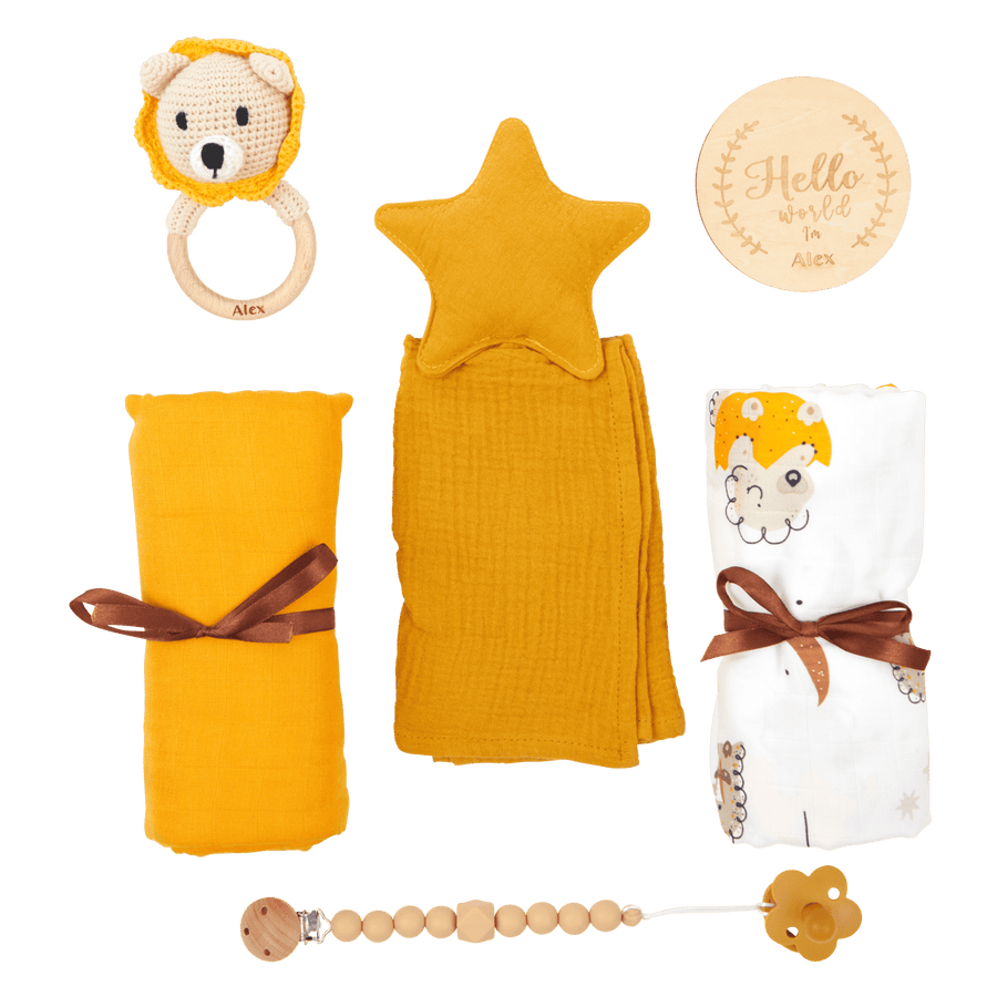 A personalised newborn gift set including a yellow star-shaped comforter, a crochet lion rattle, a white and yellow striped pacifier holder, a brown and yellow decorative bow, and a round name tag.