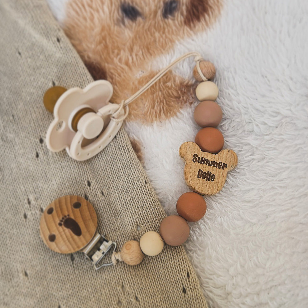 Personalised bear dummy clip with pacifier on a textured surface