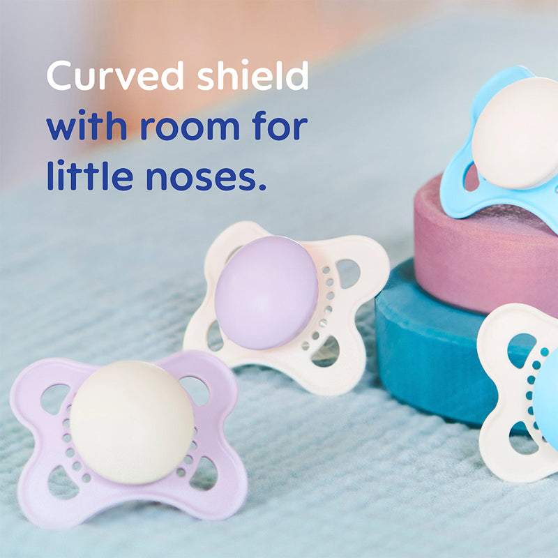 Baby pacifiers dummies with curved shields on a soft blue background