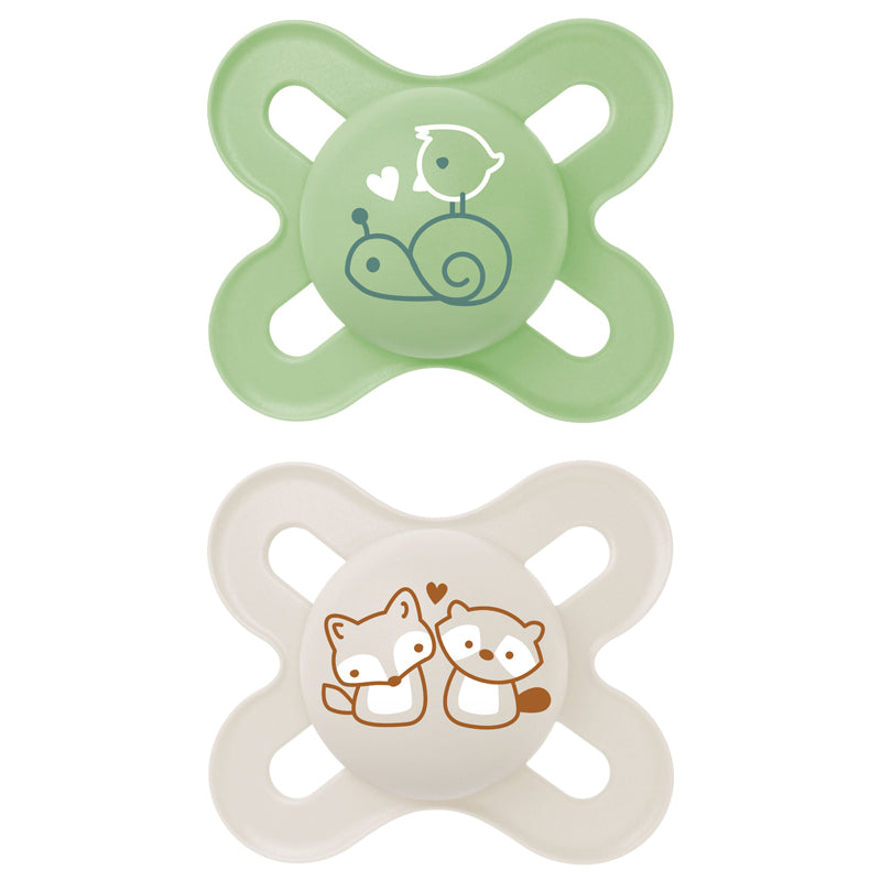 Two MAM baby pacifiers dummies, one green with a snail design and one beige with fox designs, on a white background.