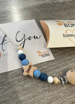 Personalised dummy clip with wooden and silicone beads on a wooden surface with Newly Born Packaging